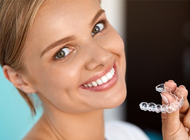 woman with straight smile holding aligners