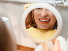 Patient with clear aligners smiling at reflection in mirror