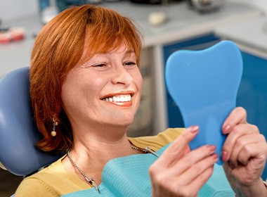 A woman looking at her dentures in a mirror