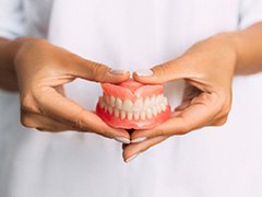 A woman holding a pair of dentures