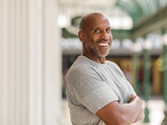 Man in gray shirt smiling outside