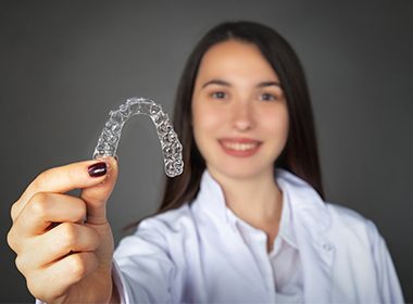 woman holding up invisalign