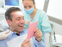 dental patient admiring his smile in a mirror 