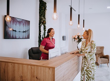 Dental receptionist and patient smiling in lobby
