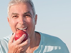 Man in blue shirt biting into a red apple