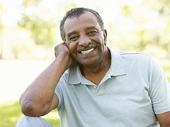 Man in grey polo smiling outside