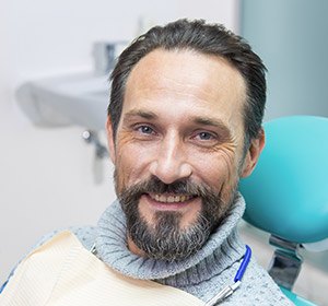 man in grey turtleneck smiling