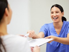 Smiling dentist handing patient forms