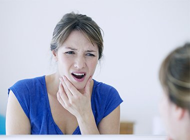 woman holding jaw in pain