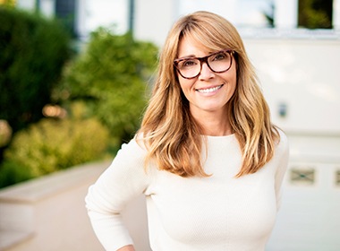 Woman in white sweater smiling outside