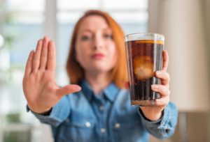 Woman holding soda and doing “stop” sign with other hand