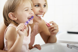 Mother and daughter brushing their teeth in bathroom