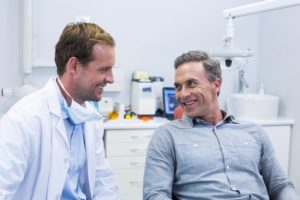 Dentist and patient smiling and discussing health factors