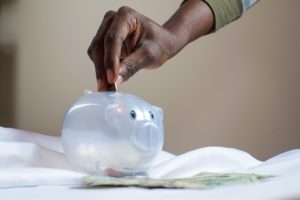 Man placing coin in clear piggy bank