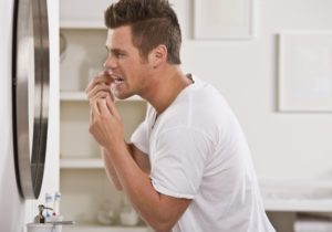 man flossing in mirror