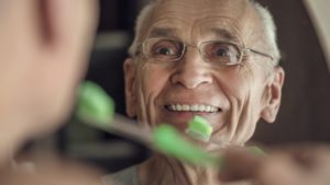 mature man brushing his teeth in bathroom