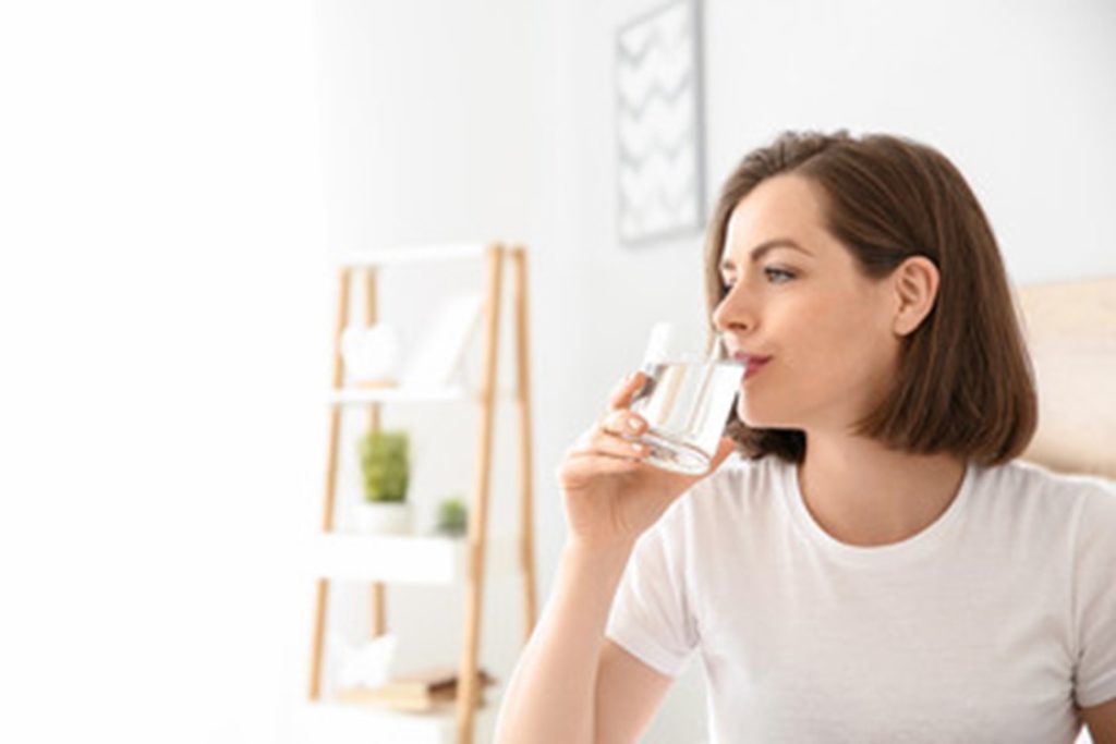 Woman drinking a glass of water to stay hydrated.