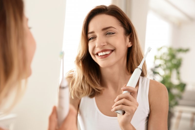 Woman with toothbrush smiling in the mirror