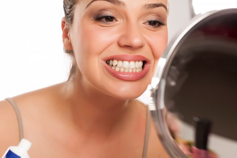 woman checking her teeth before seeing dentist in Lehigh Valley