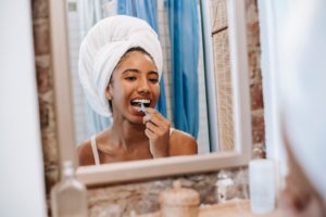 Woman looking in mirror to floss her teeth