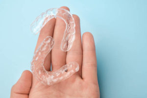 Hand holding set of clear aligners
