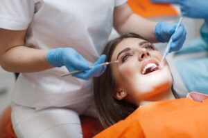 Dentist in white scrubs examining woman's teeth