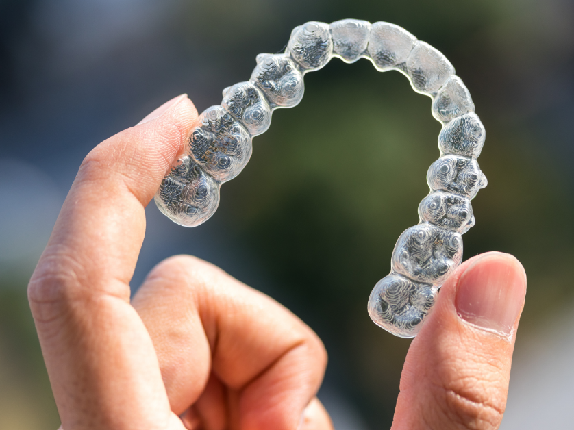 Hand holding Invisalign retainer
