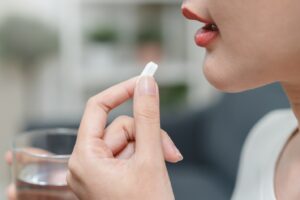 Person holding a pill and a glass of water