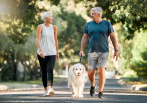 Woman and man outside walking dog on the road together